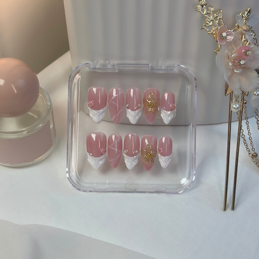 Blossoming press-on nails in their Lunoxcore clear display box — rose-pink base with silver chrome tips and intricate golden floral details that evoke elegance and warmth.