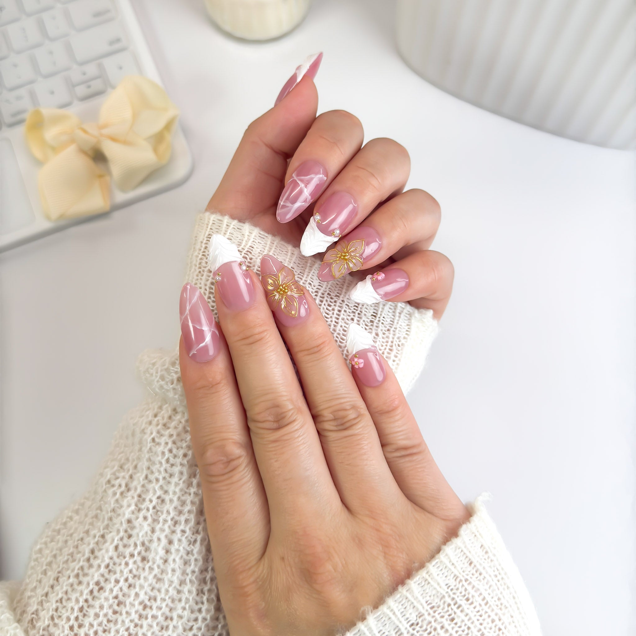 Blossoming nails photographed from an angle to highlight their smooth rose finish, silver chrome edges, and golden floral artistry.