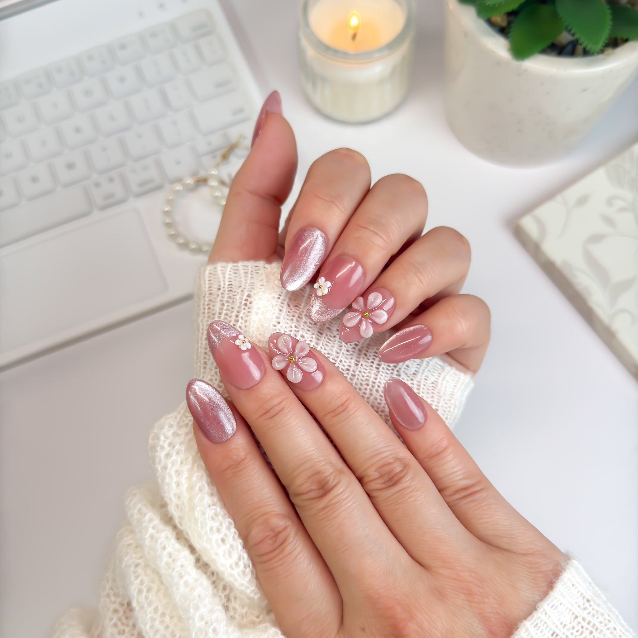 Daisy Daze press-on nails styled under candlelight — pink shimmer finish with handcrafted daisies for a fresh, radiant glow.