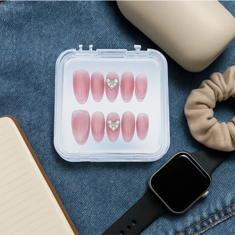 Lunoxcore reusable press-on nails styled for everyday wear — soft pink nails with heart embellishments in a compact case beside a smartwatch and notebook, symbolizing daily elegance and versatility.