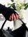 Lunoxcore handcrafted press-on nails with silver accents, styled on natural hands holding a black handbag beside white florals — symbolizing confidence, creativity, and beauty with an extra touch.