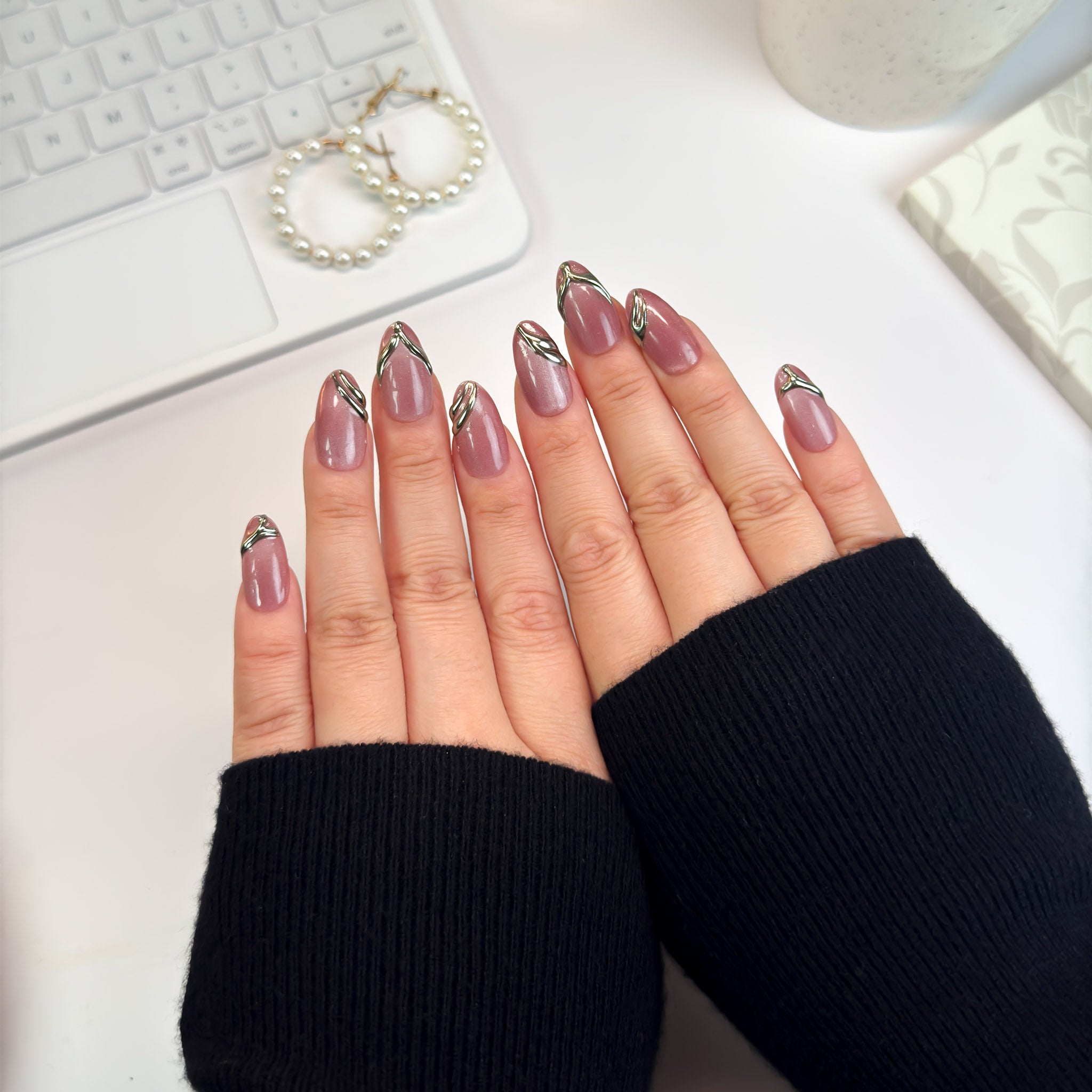 Top-down view of Gilded Strike nails — matte mauve press-ons with reflective gold chrome accents, merging strength and sophistication.