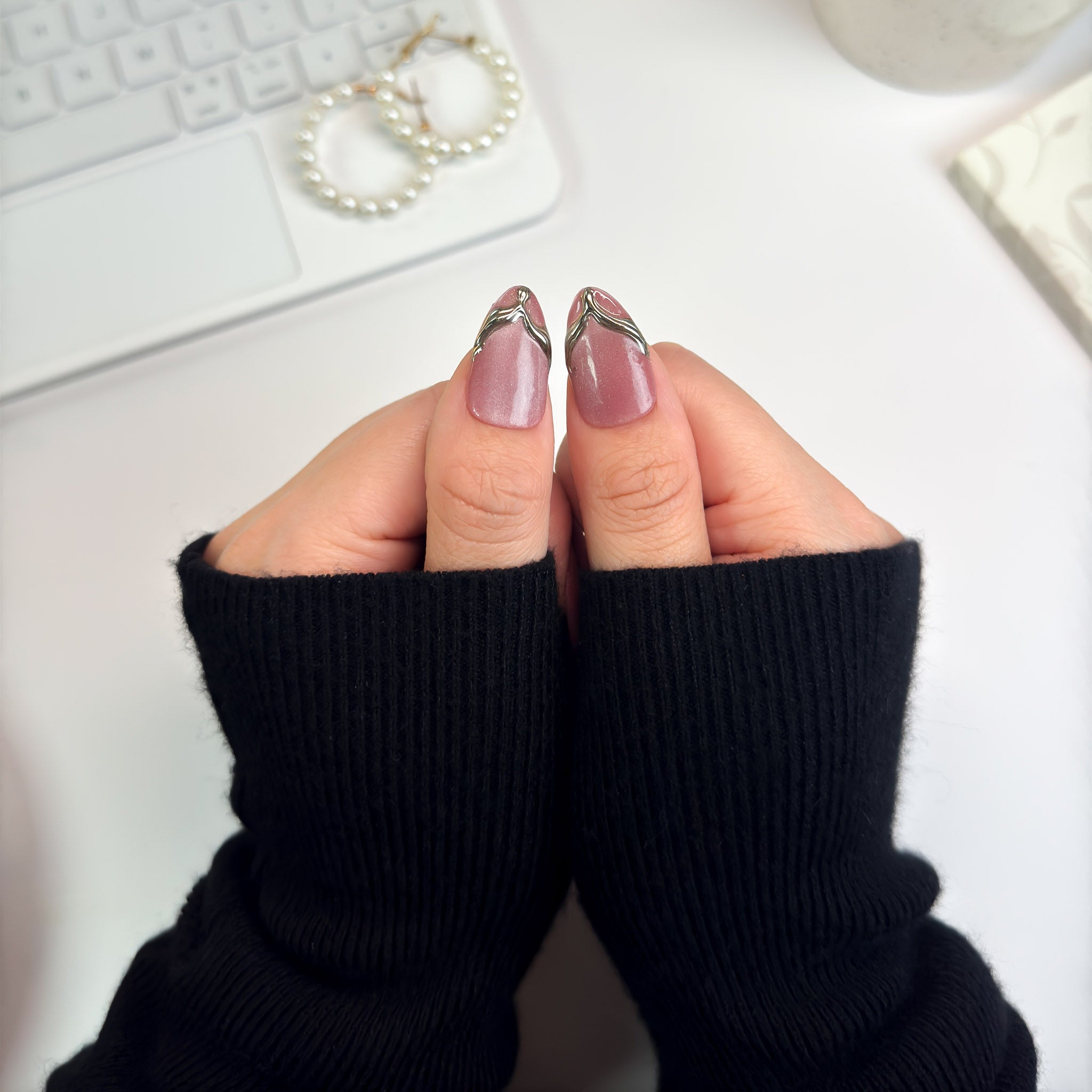 Close-up of Gilded Strike nails showing metallic gold molten designs flowing across a soft mauve base — minimal yet striking.