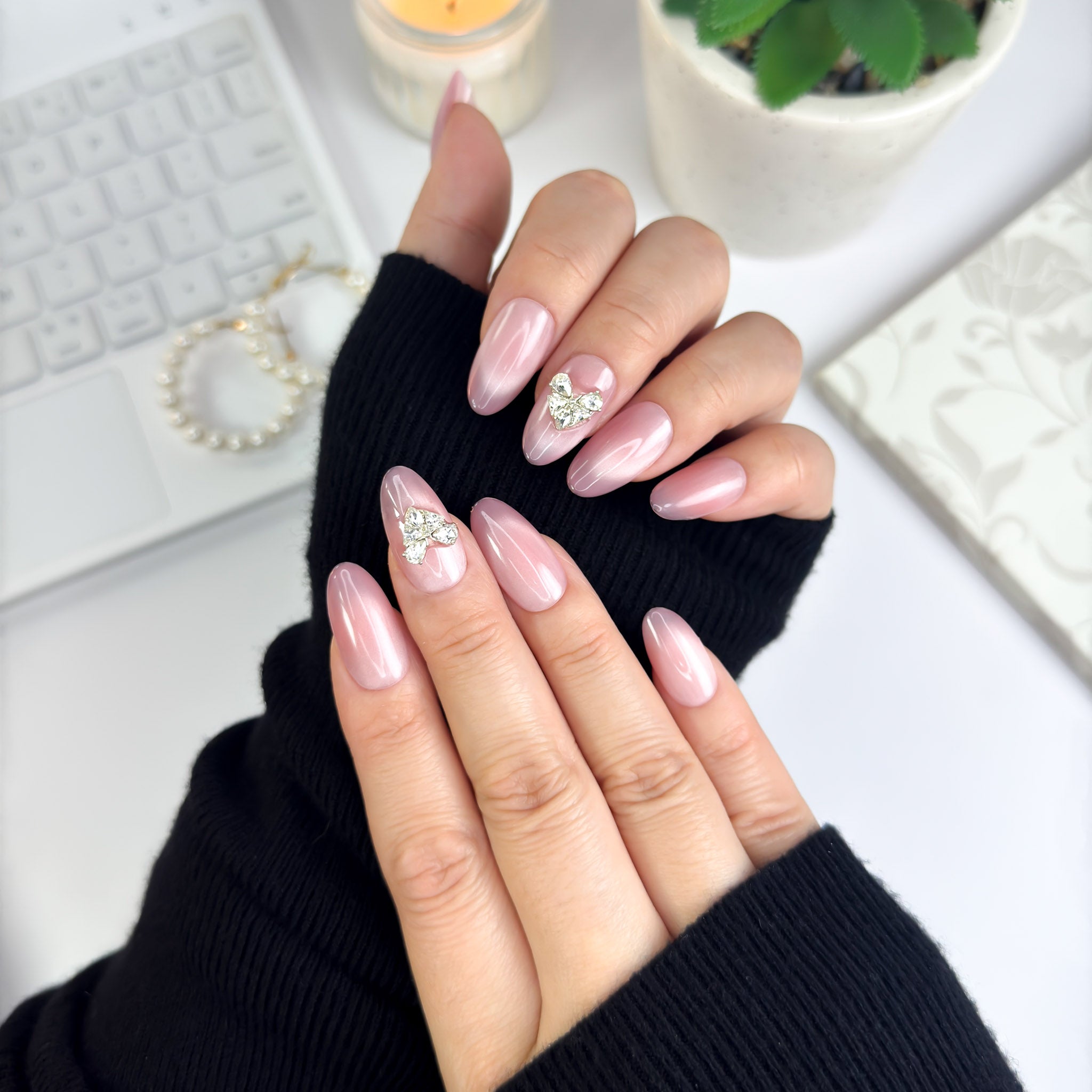 Angled hand pose of Magnetic Love nails — soft pink base with crystal heart centerpiece, radiating warmth and elegance.