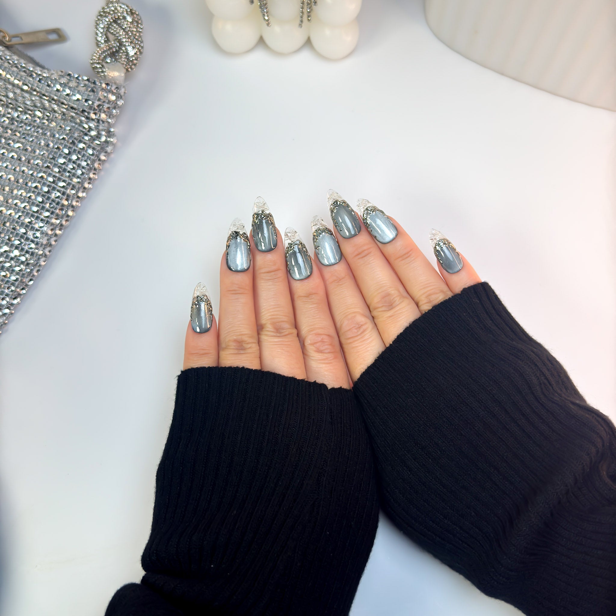 Top-down view of Molten Glass nails showing the gradient from metallic charcoal to crystal-clear tips with shimmering silver texture.
