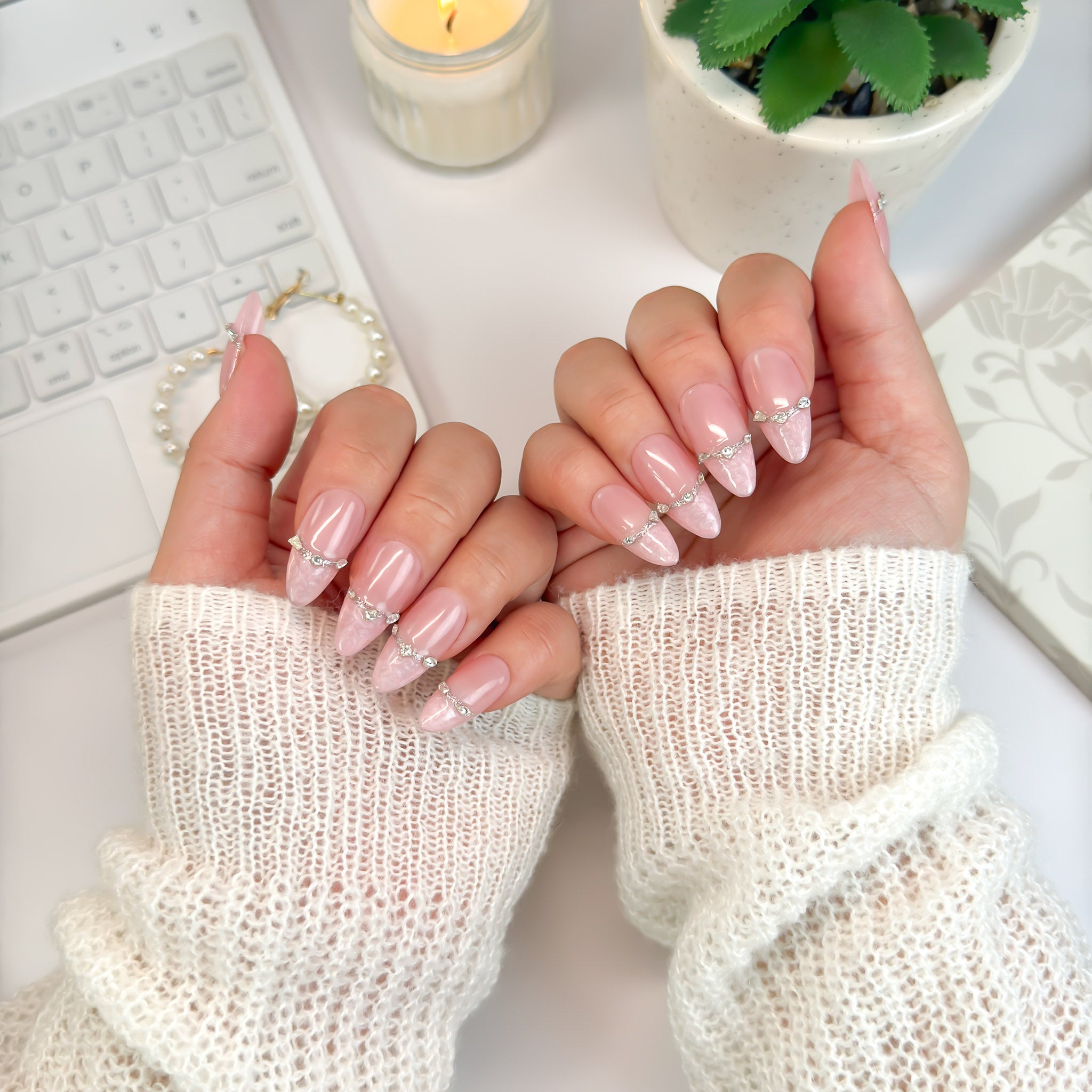 Angled hand pose of Rose Reverie press-on nails — light pink shimmer and gemstone chain details adding elegance and radiance.