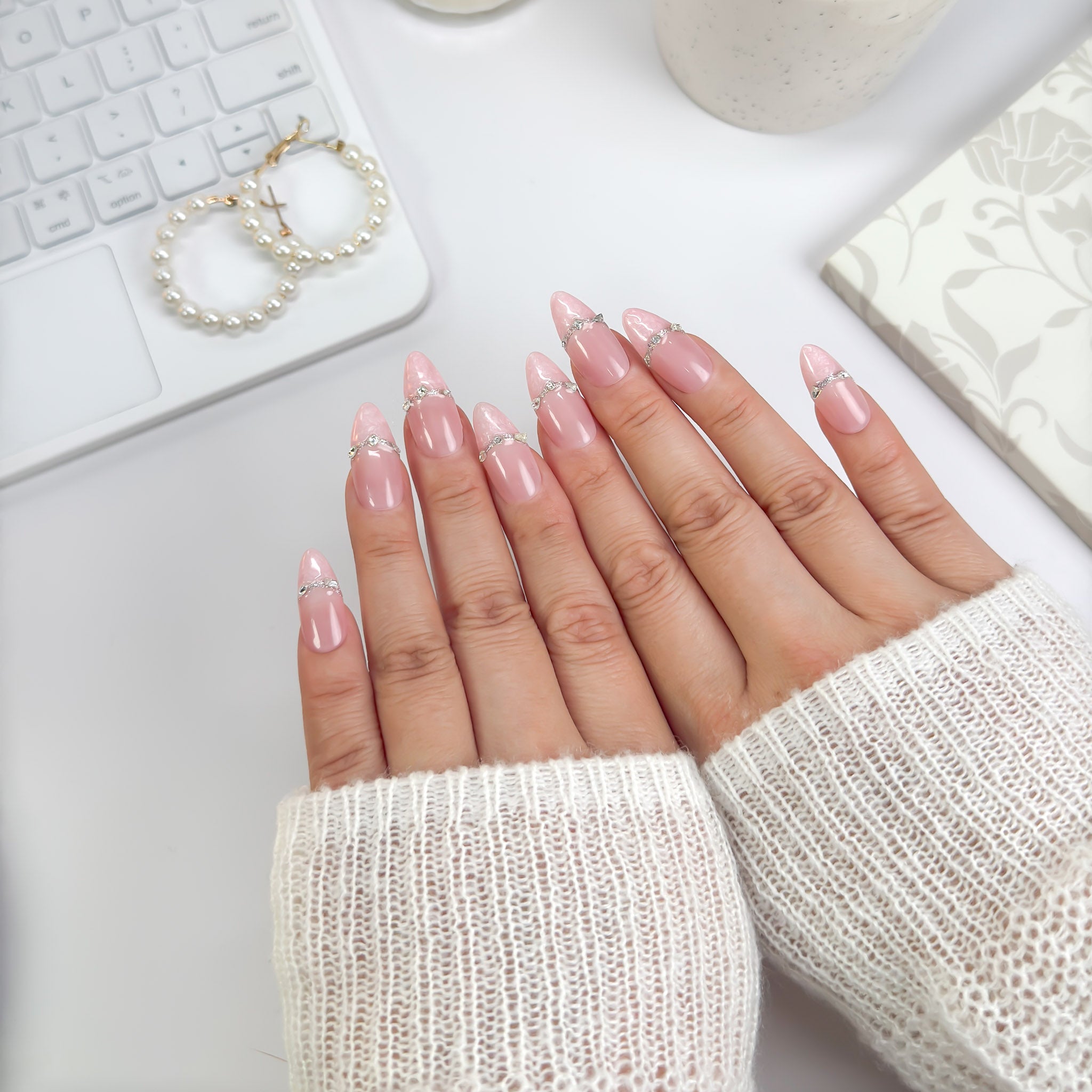 Rose Reverie press-on nails photographed under candlelight — soft pink hues, intricate lace textures, and sparkling gem accents exuding romantic charm.