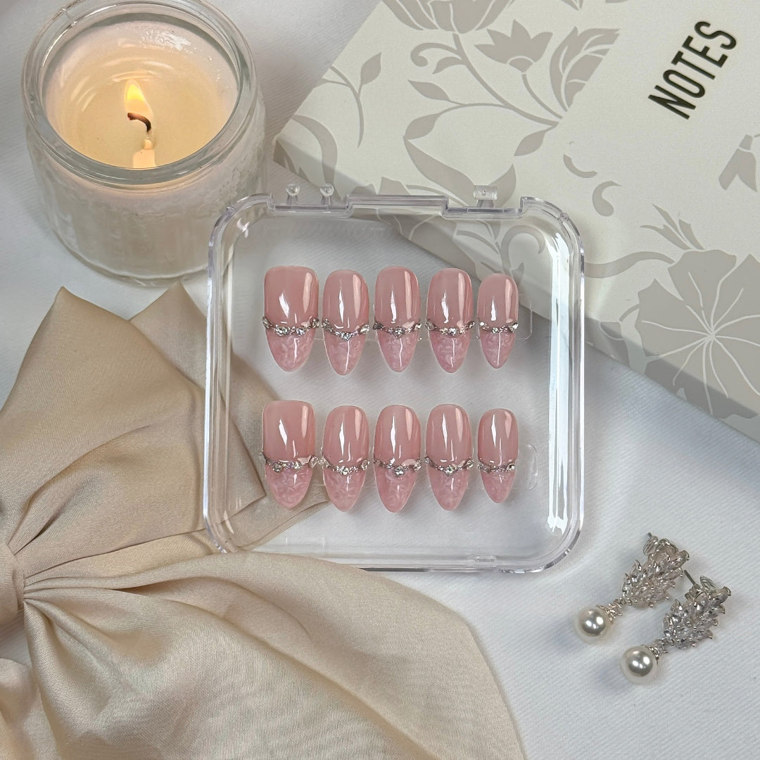 Rose Reverie press-on nails by Lunoxcore — delicate pink tones with crystal embellishments and lace-like tips, displayed elegantly in a clear case.