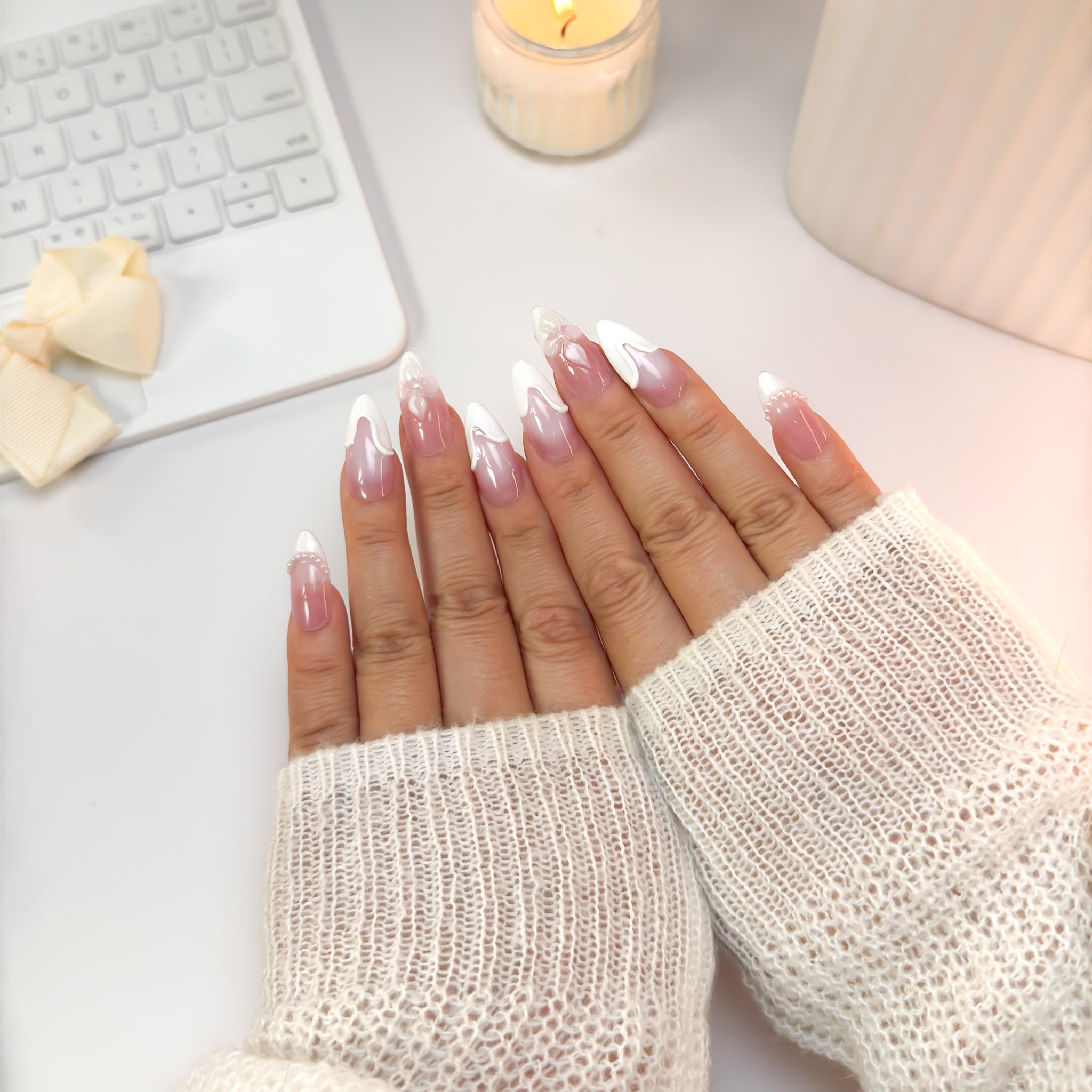 Top-down view of Soft Serve nails — soft pink with sculpted white swirls and pearl details, glowing with graceful sweetness.