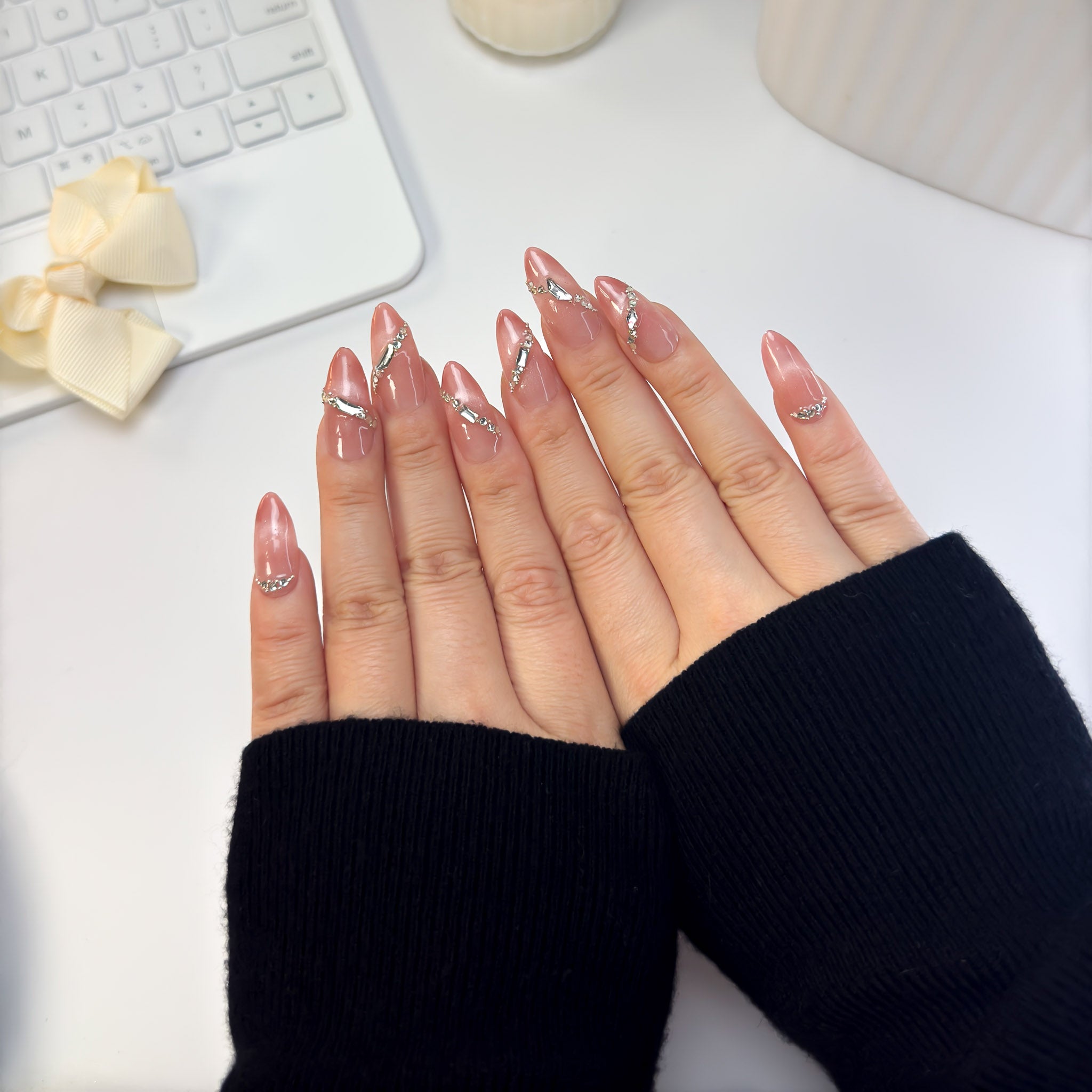 Top-down view of Sunlit press-on nails featuring soft peach tones and radiant shimmer, glowing under natural sunlight with effortless elegance.