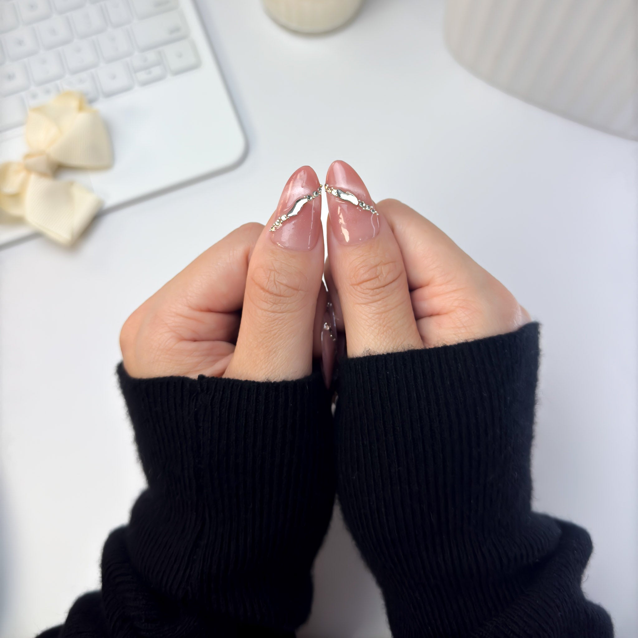 Close-up of Sunlit press-on nails showing glossy peach-pink tones and subtle gold shimmer, captured in natural sunlight for a radiant glow.