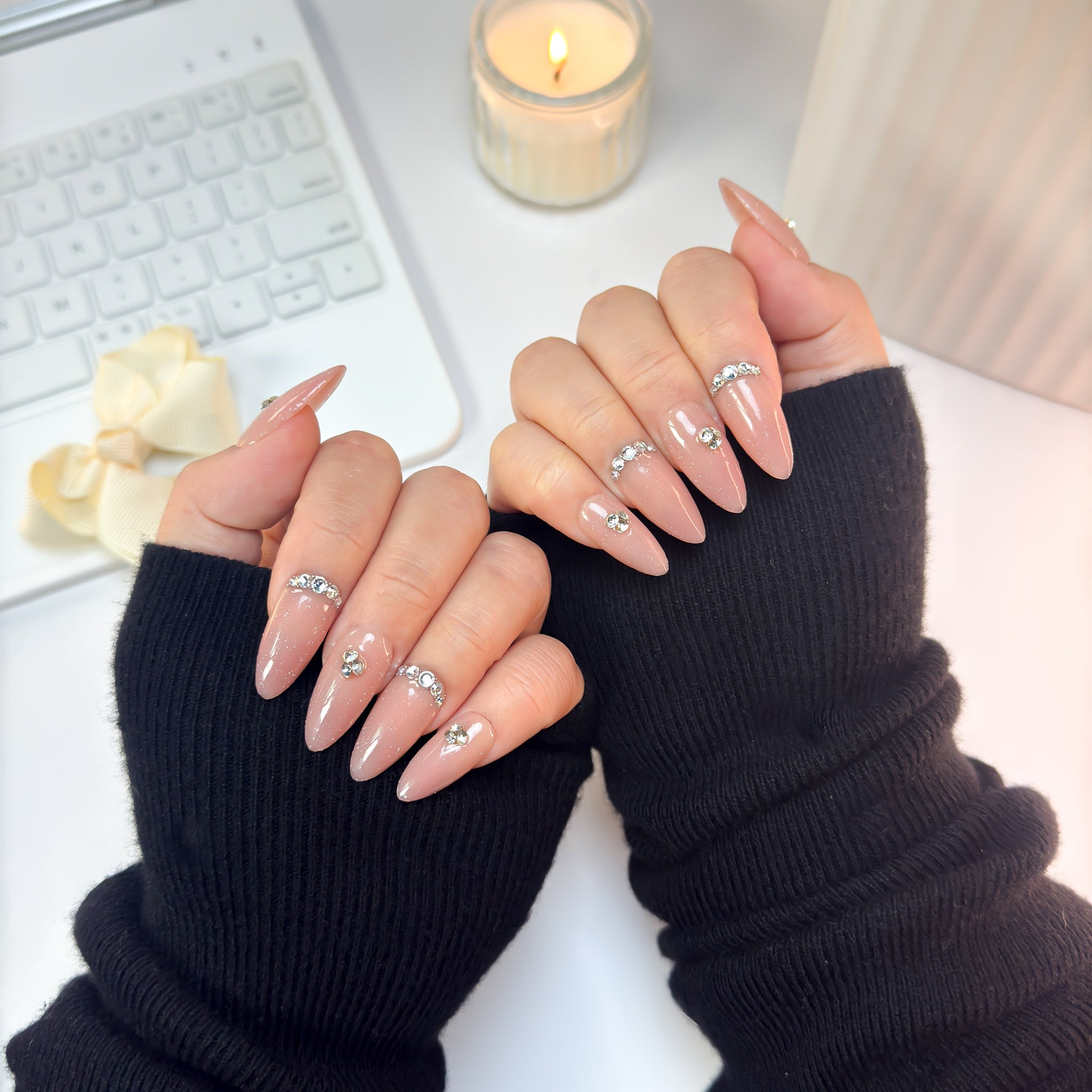 Top-down view of Twinkle Touch press-on nails — a refined nude-pink design adorned with subtle sparkle and crystal charm, glowing softly in every light.
