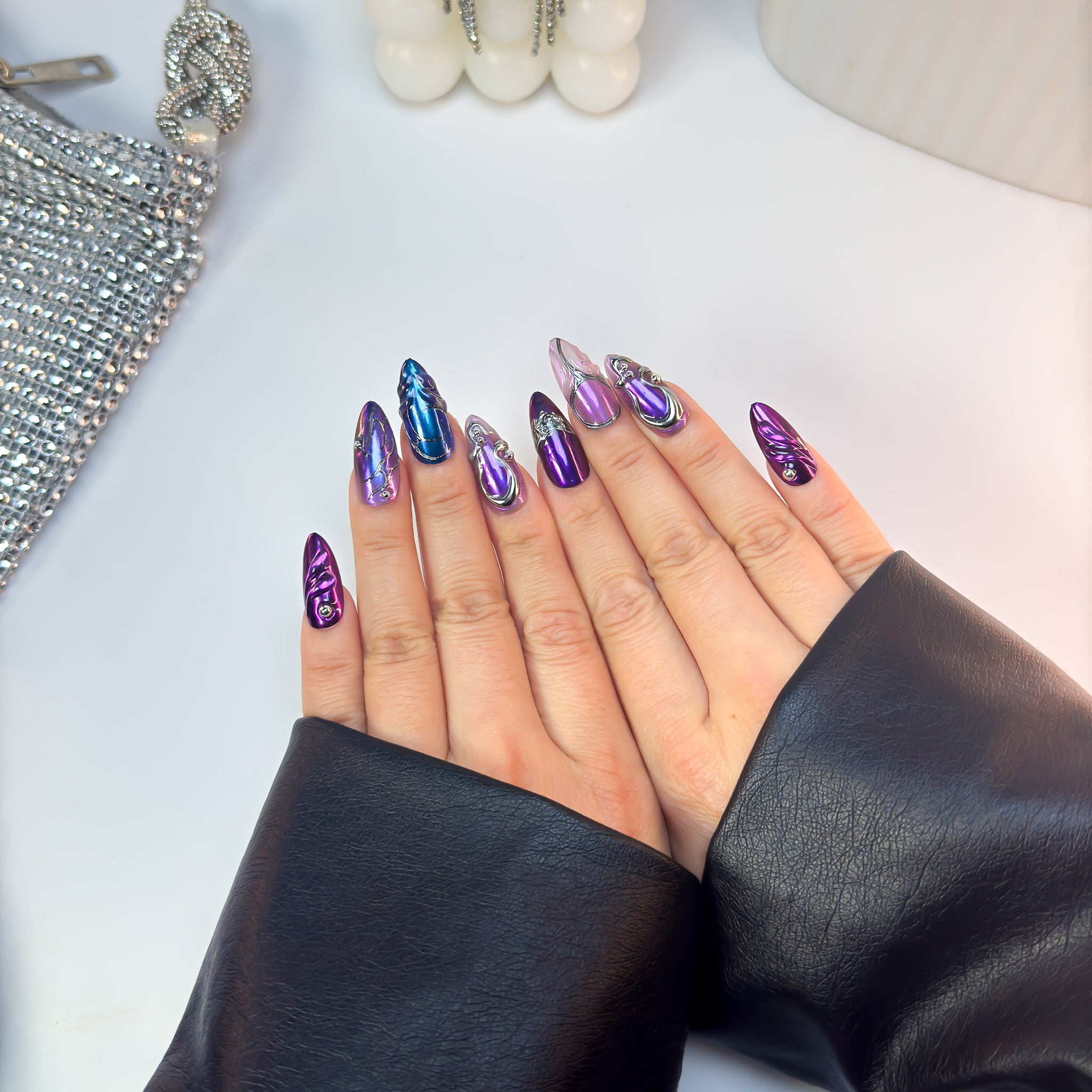 Full set of Ultraviolet press-on nails with ombré violet-blue chrome finish and raised metallic accents, shown from a top-down view.
