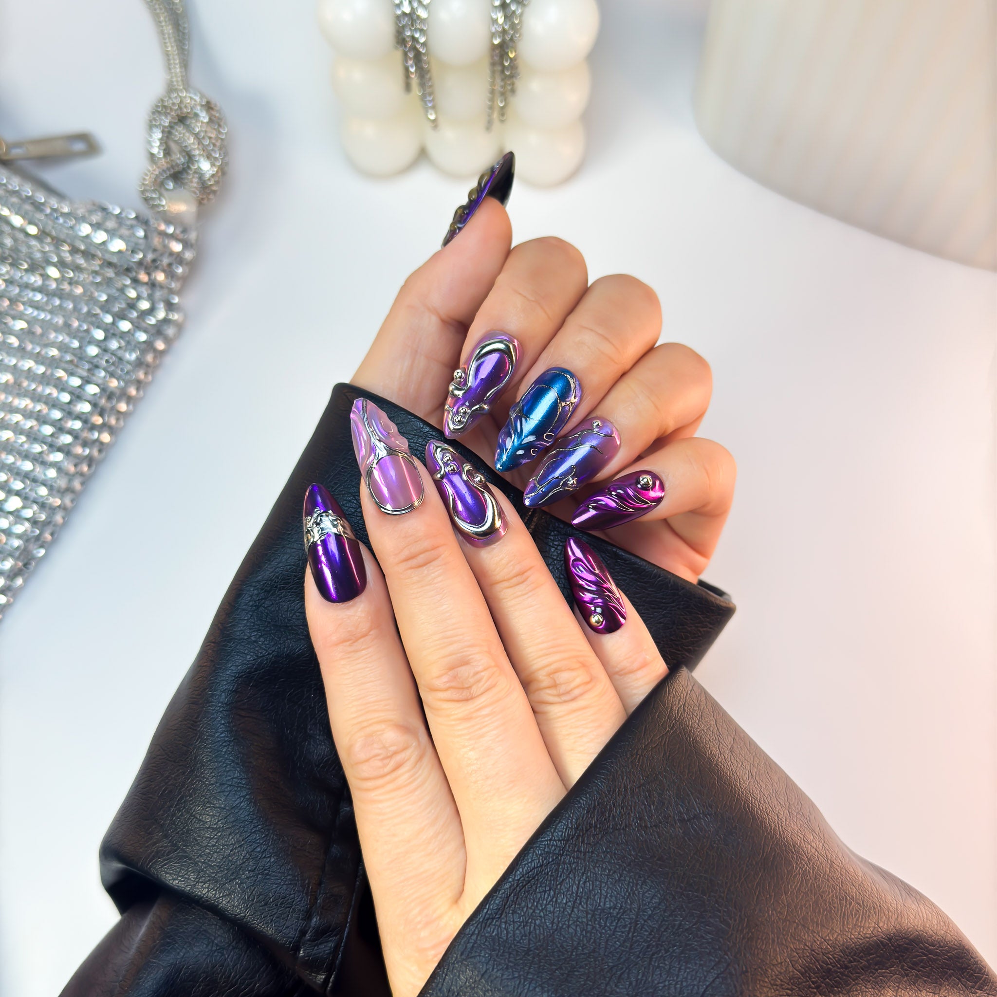 Ultraviolet press-on nails featuring gradient purple and blue chrome tones, shown in an angled hand pose for detail emphasis.