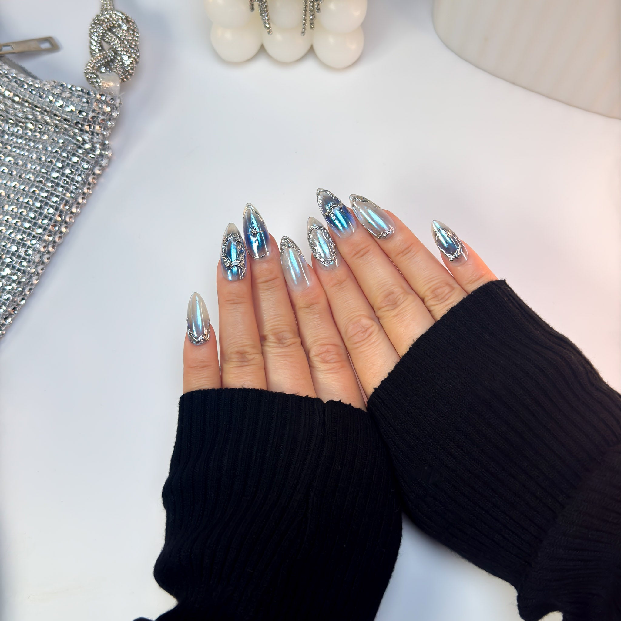 Top-down view of Voltage press-on nails featuring metallic blue chrome and reflective silver design across both hands.