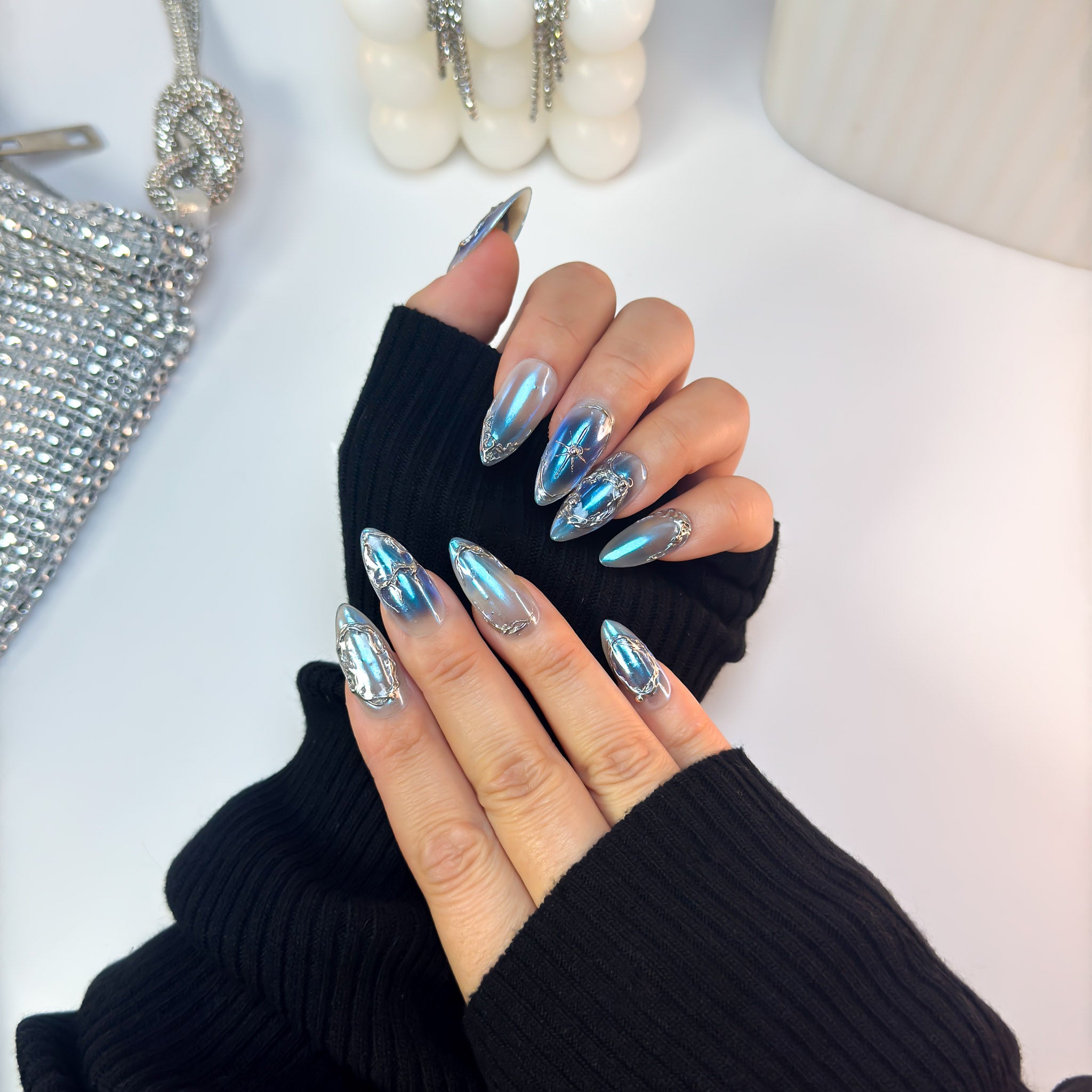 Voltage press-on nails in a metallic blue chrome finish with futuristic silver accents, displayed in a cross-hand angle pose.